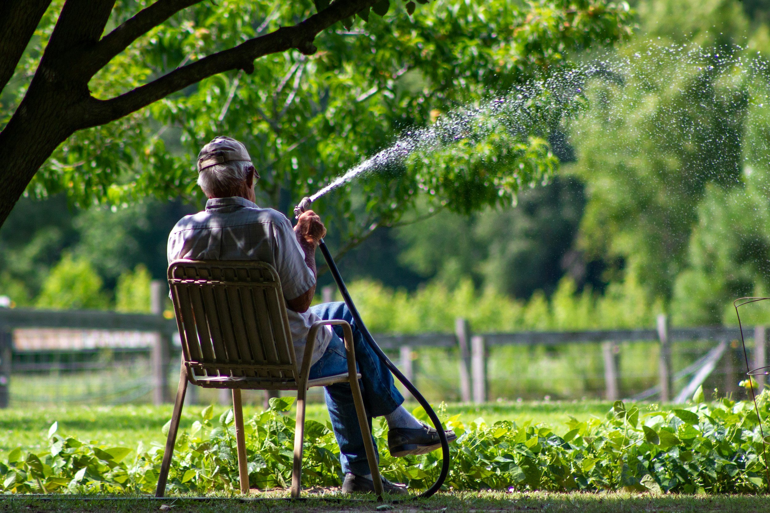 Man manually watering lawn - let our sprinkler systems do this work for you